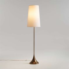 a floor lamp with a white shade on the base and a cord attached to it