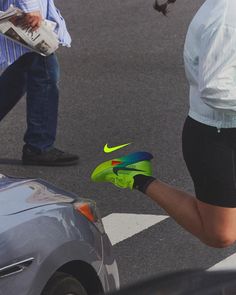 a person with green and blue gloves is crossing the street while another person walks by