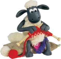 a stuffed sheep sitting on top of a pile of wool with a knitting needle in it's mouth