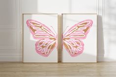 two pink and gold butterfly paintings in a white room with wood flooring on the side