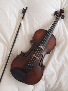 an old violin laying on top of a white sheet