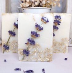 three soap bars with dried lavender flowers on them sitting next to a potted plant