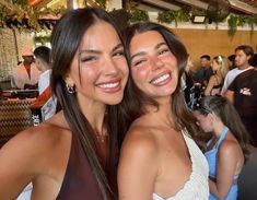 two beautiful young women standing next to each other in front of a group of people