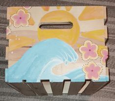 a painted wooden box with flowers and a wave on the ocean in front of a sun