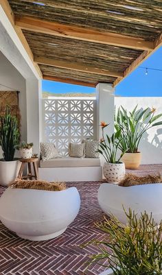 some plants are sitting in large white bowls on the ground near an outdoor seating area