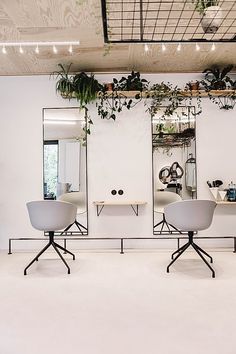 two white chairs sitting next to each other in front of mirrors