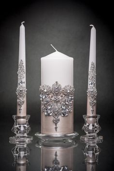 three white candles with crystal decorations on them