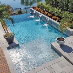 an outdoor swimming pool surrounded by trees and water features two large planters on either side