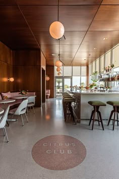 an empty restaurant with tables and stools in the foreground, on which is a circular sign that reads citrus club