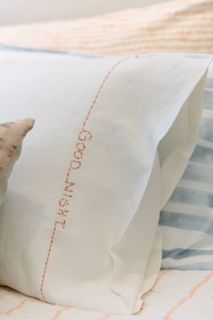 a close up of a pillow on top of a bed with white and orange pillows