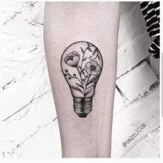 a black and white tattoo of a light bulb with flowers