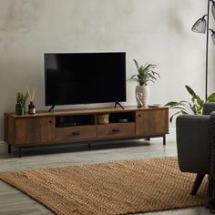 a large flat screen tv sitting on top of a wooden entertainment center in a living room