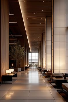 an empty lobby with couches and tables on the floor, in front of large windows