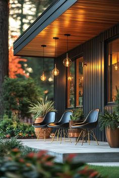 some chairs are sitting outside on the porch near potted plants and lights hanging from the roof