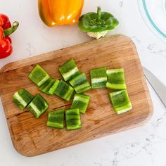 sliced up cucumbers sit on a cutting board next to peppers and bell peppers