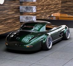 a green sports car is parked in front of a building with wood panels on the walls