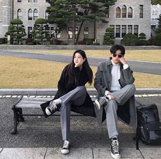 two people sitting on a bench in front of a building