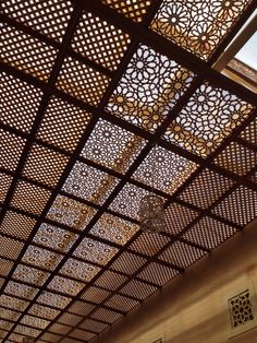 the ceiling is made up of metal lattices and wood panels with decorative designs on them