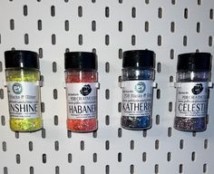 three jars of different colored glitters on a wall