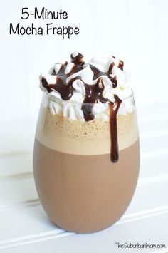 a glass filled with chocolate and marshmallows on top of a white table