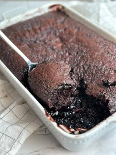 a close up of a cake in a pan on a table with a spoon and napkin