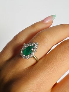 a woman's hand with an emerald and diamond ring