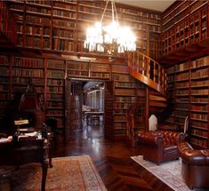 a room with many bookshelves and leather chairs in front of a chandelier