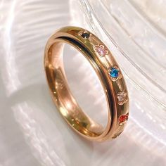 a gold ring with multicolored stones on the inside is sitting on a white surface