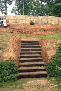 a set of steps leading up to a fenced in area with trees and bushes