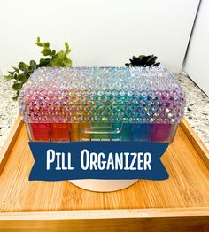 the pill organizer is sitting on top of a wooden tray