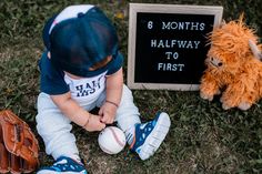 a little boy sitting in the grass with a baseball and glove next to him is a sign that says 6 months halfway to first