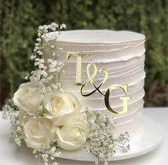 a wedding cake with white flowers and the initials t and g on it's side