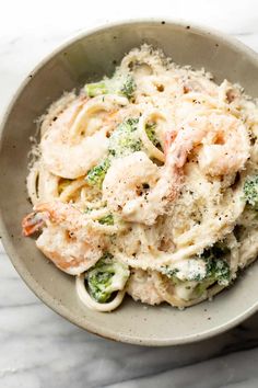 pasta with shrimp and broccoli in a white bowl on a marble countertop