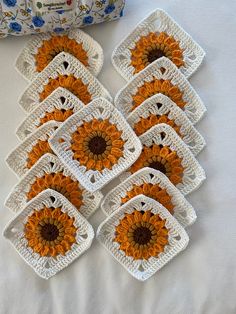 six crocheted coasters with orange and white flowers on them next to a bag