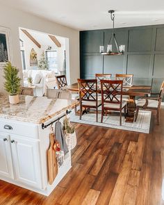 an open concept kitchen and dining room with wood flooring, white cabinets and countertops