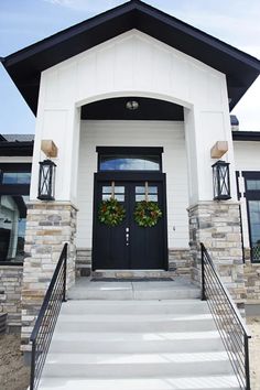 a black and white house with two wreaths on it's front entrance steps