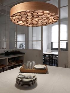 a wooden light fixture hanging over a dining room table with plates and glasses on it