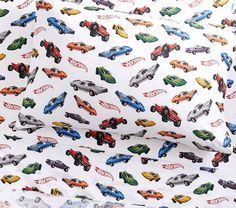 a white sheet with colorful cars printed on the top and bottom part of it,