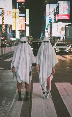 two people in ghost costumes walking down the street