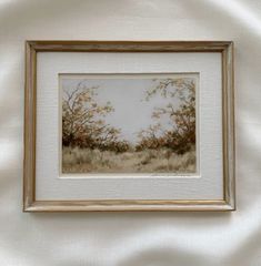 a painting hanging on the wall in a room with a white curtain and a brown frame