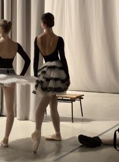 two ballerinas are standing in front of a white curtain and one is wearing a tutu