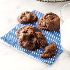 chocolate cookies on a blue napkin next to a glass of milk