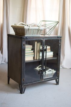 an old bookcase with books and a basket on top is sitting in front of a curtained window