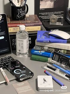 an open laptop computer sitting on top of a desk next to books and other items