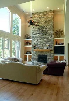 a living room filled with furniture and a fire place in front of a stone fireplace