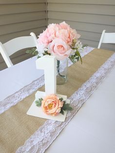 a vase with flowers on top of a table next to a white chair and lace runner