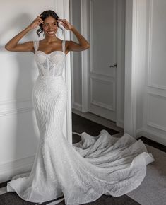 a woman in a white wedding dress standing next to a wall with her hands on her head