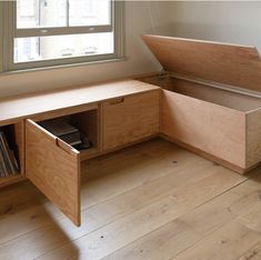 an open storage bench in front of a window with books and records on the bottom shelf