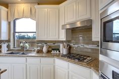 a kitchen with white cabinets and granite counter tops, along with a stove top oven