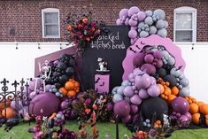 an outdoor halloween display with balloons and decorations on the grass, in front of a brick building